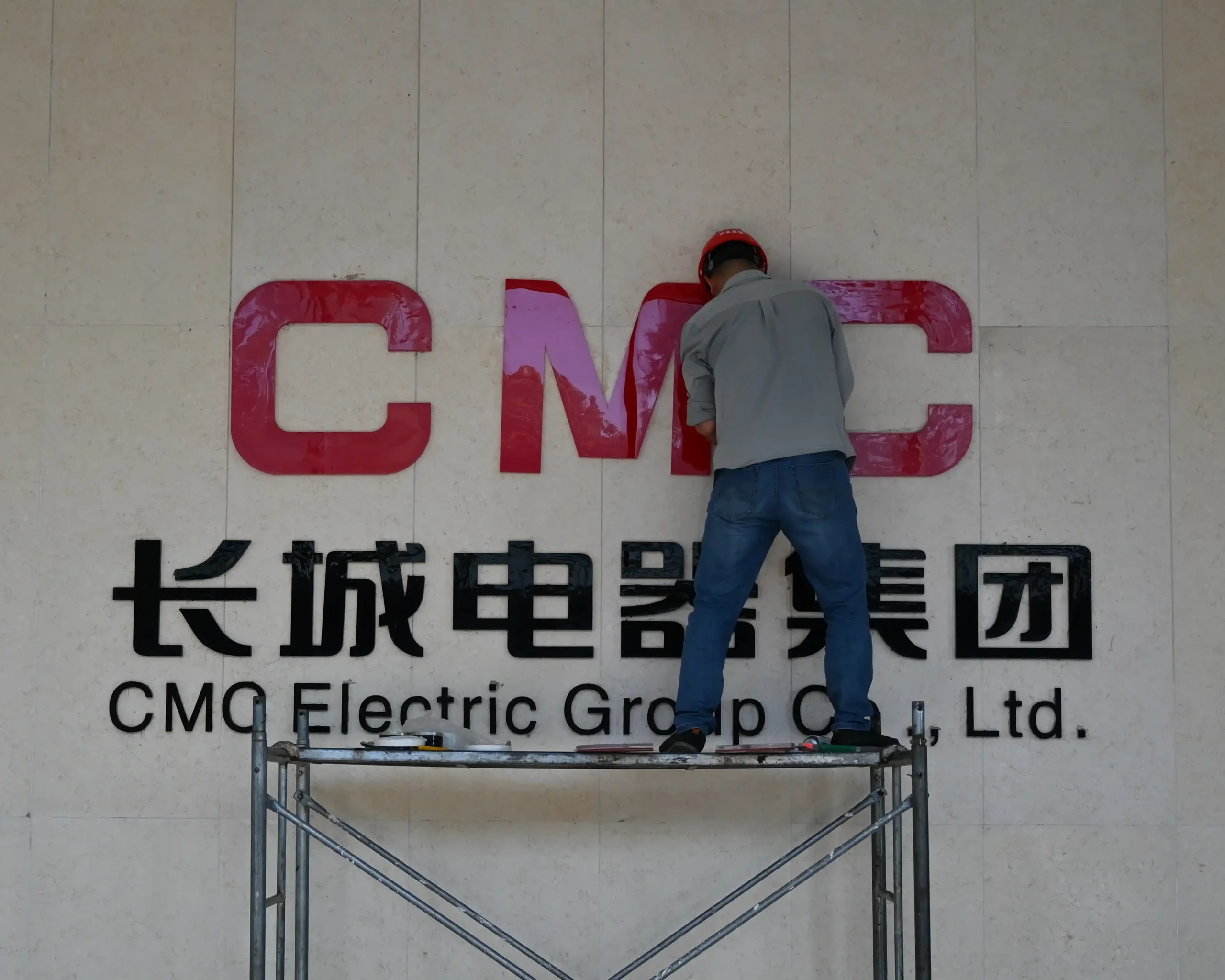 Worker installing CMC signage during the launch of the CMC brand